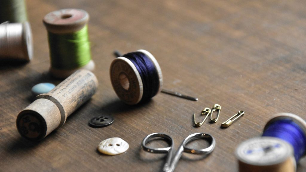 a wooden table topped with lots of sewing supplies